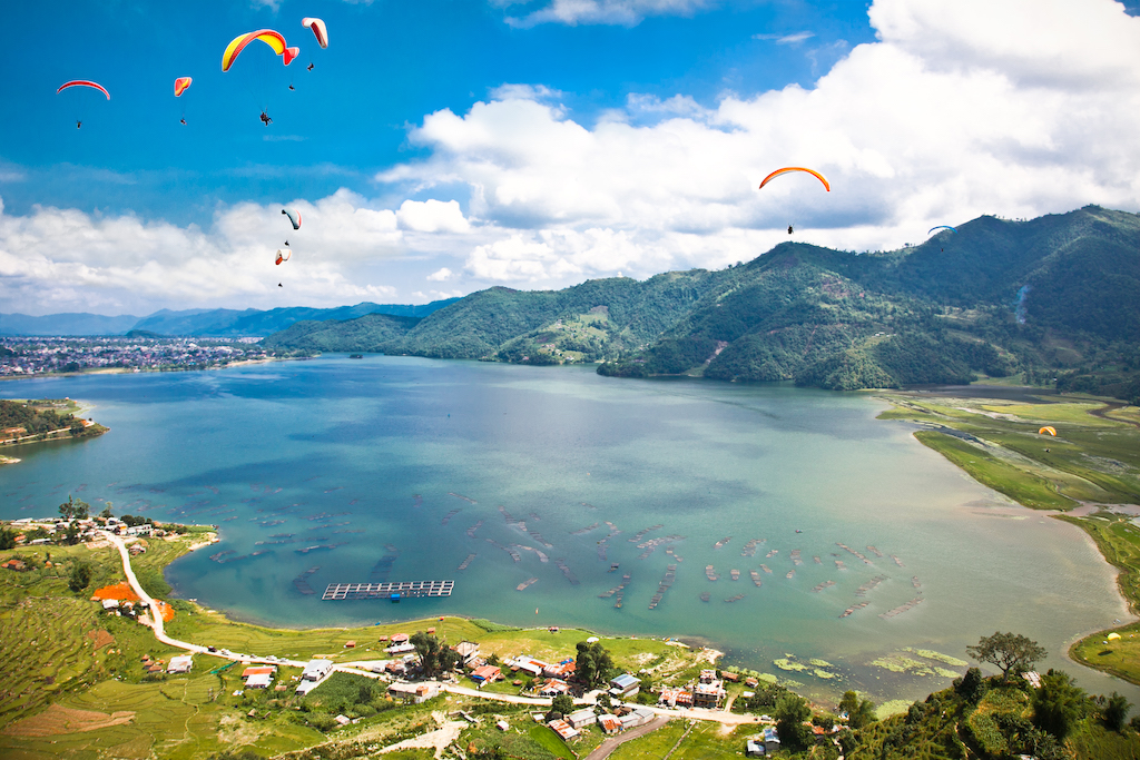 Paraglider flying over the Fewa lake in Pokhara, Nepal.